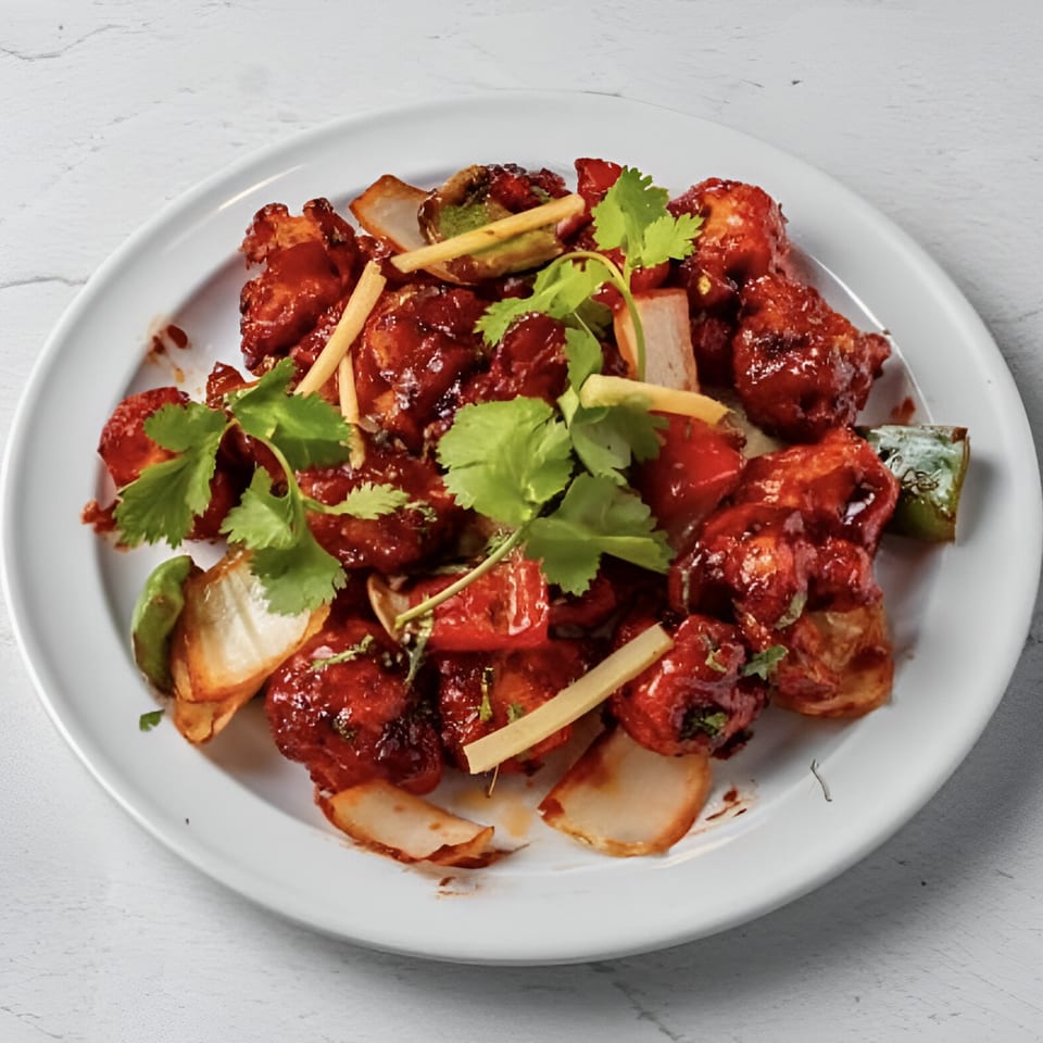 Taj Darbar Indian Cuisine's chili chicken, garnished with cilantro, ginger, and onions.