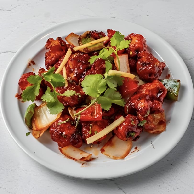 Taj Darbar Indian Cuisine's chili chicken, garnished with cilantro, ginger, and onions.