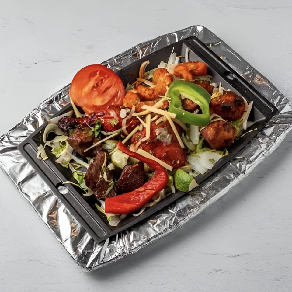 Taj Darbar Indian Cuisine's sizzling platter with chicken, lamb, shrimp, vegetables, and spices.