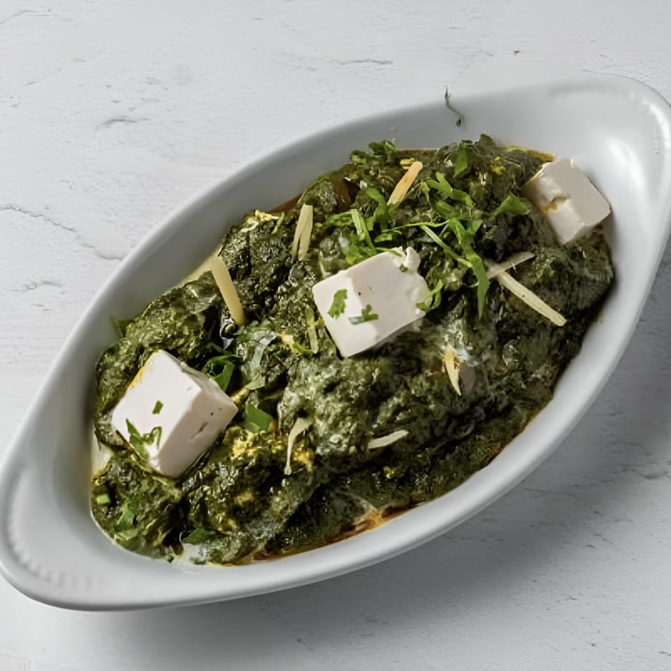 Taj Darbar's Palak Paneer, a vibrant green spinach dish with white paneer cubes and ginger slivers.